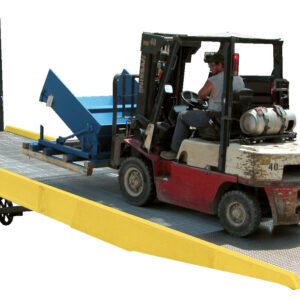 A forklift operator skillfully ascends a Vestil Yard Ramp with Option-Yellow Curb Paint, guiding it into a truck trailer. The forklift, carrying a large blue object, moves seamlessly amidst the lively industrial loading dock.