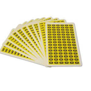 A fanned set of MH-USA Complete Packs of Self-Adhesive Numbers in yellow, with black numbers and symbols, is displayed on a white background. The front card features a grid of black ovals, dimensions: H.0.33 in. x W.0.49 in.