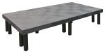 The Quantum Polymer Dunnage Rack is a solid rectangular platform with a flat gray surface and circular indentations, supported by black cylindrical legs, crafted from polyethylene with a 1900 lb. load capacity and proudly made in the USA.